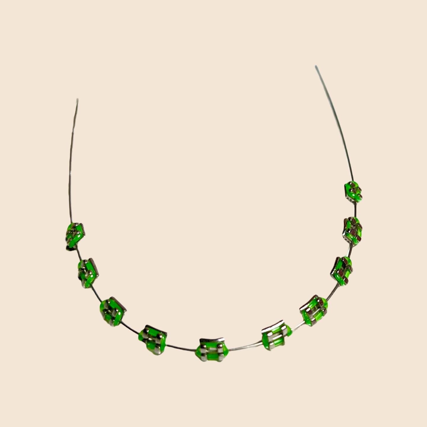 Green handmade doll braces with metallic brackets on a wire, shown as a color variant of a DIY cosplay accessory kit forThe monster Labubu dolls. Adhesive tools included. Doll not included.