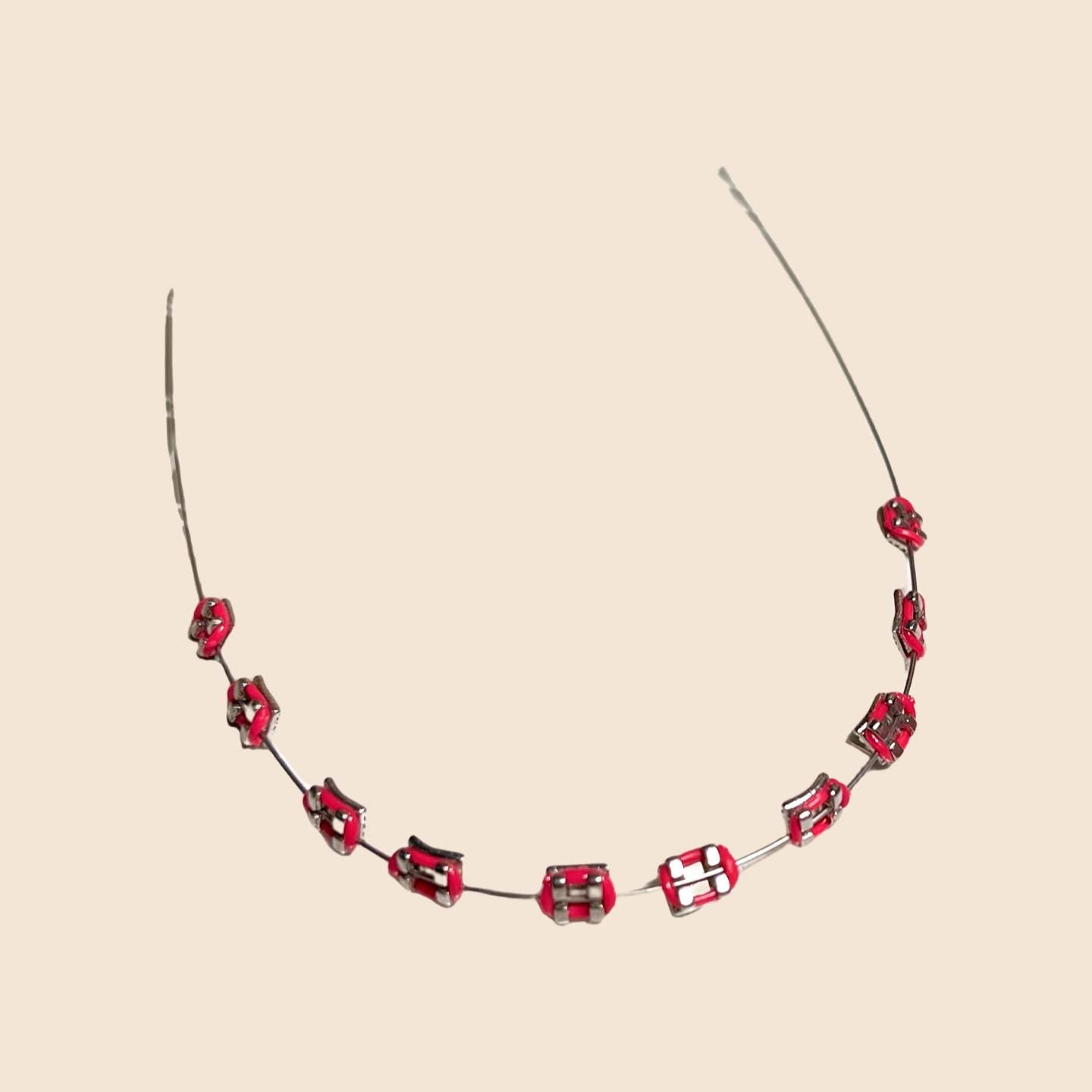 Red handmade doll braces with glossy metallic brackets arranged on wire, featured as a color variant in a DIY cosplay accessory kit forThe monster Labubu dolls. Adhesive tools included. Doll not included.