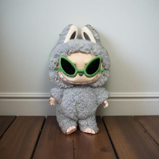 Labubu doll wearing a fluffy bunny costume with oversized green cyberpunk sunglasses, posed on a wooden floor. Doll not included.