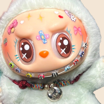 Close-up of a Labubu doll wearing colorful handmade fake braces with detailed beads on each tooth, part of a DIY accessory kit for 15cm–38cm dolls. Includes adhesive tools. Doll not included.