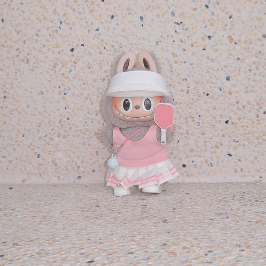 Labubu doll in pink pickleball outfit with visor and paddle, standing against terrazzo beige background, Popanion handmade doll fashion